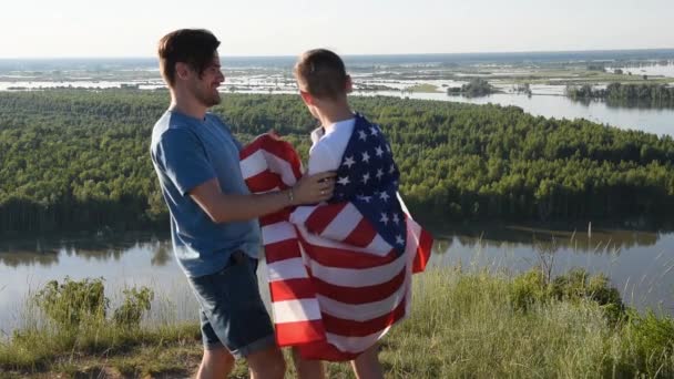 Lindo joven y su padre sosteniendo en alto la bandera americana — Vídeos de Stock