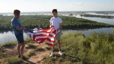 Sevimli genç bir çocuk ve babası Amerikan bayrağını havada tutuyorlar.
