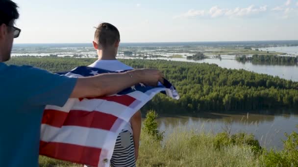 Милий молодий хлопчик з батьком тримаються вгору по американському прапору. — стокове відео