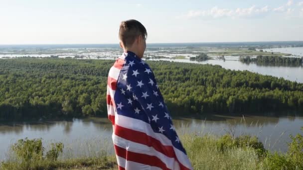 Blond pojke viftar nationell USA flagga utomhus över blå himmel vid floden banken — Stockvideo