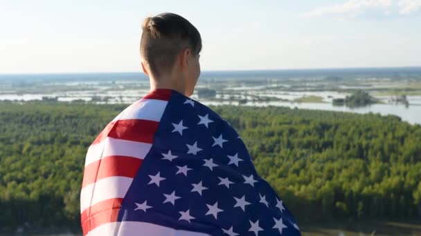 Αγόρι κυματίζει εθνική σημαία των ΗΠΑ σε εξωτερικούς χώρους πάνω από μπλε ουρανό στην όχθη του ποταμού — Αρχείο Βίντεο