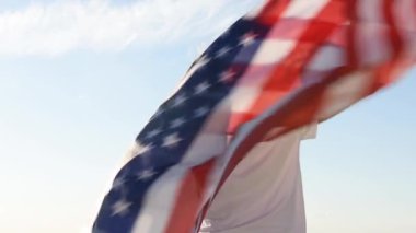 Sarışın çocuk nehir kıyısında mavi gökyüzünde ulusal Amerikan bayrağı sallıyor.