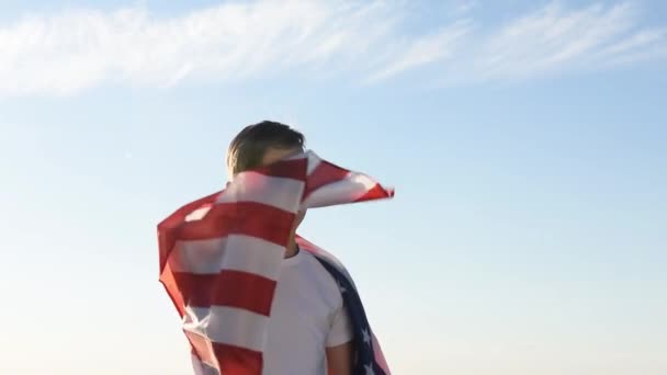 Fiú integetett nemzeti amerikai zászló szabadban a kék ég felett a folyóparton — Stock videók