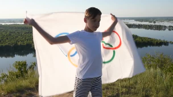 少年がオリンピックの旗を屋外で振る — ストック動画
