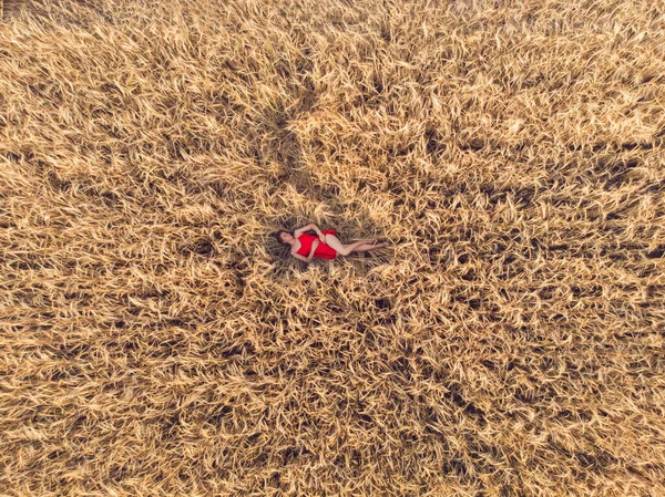 Vista aérea de la mujer en vestido rojo acostada en el campo de trigo — Foto de Stock