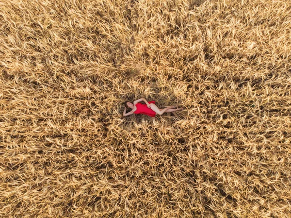 Vue aérienne de la femme en robe rouge couchée dans le champ de blé — Photo