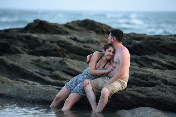 Pareja sentada en la playa de rocas — Foto de Stock