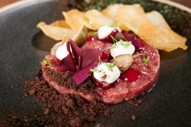 Bitki ve patates kızartması manzaralı sulu tartar eti.