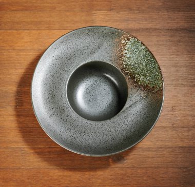 Kahverengi masanın üstünde Sombrero tarzı siyah çorba tabağı.