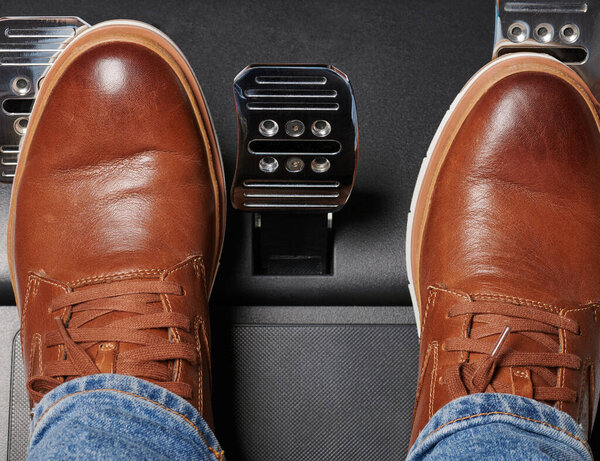 Ноги на ускорение и сцепление блестящие металлические педали автомобиля над видом сверху