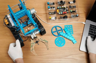 Sınıfta robotla çalışan çocuk ahşap masaya yakın çekim yapıyor.