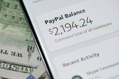 New York, ABD - 5 Ocak 2021: Dolar banknotunun arka planında akıllı telefonla ödeme yapmak