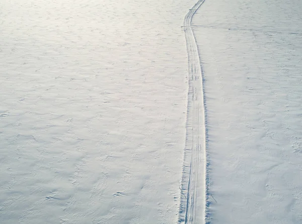 Winter car path in snowy field aerial above drone view