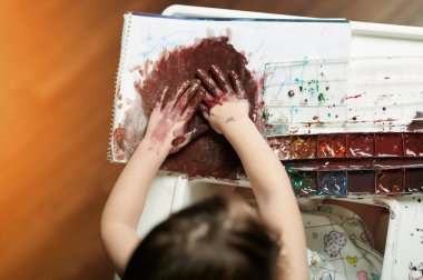 Elleri kağıt üstünde resim yapan bir kız. Anaokulu oyun teması