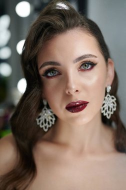 Stüdyonun arka planında makyajlı esmer kadın yüzü