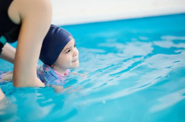 Çocuklara yüzme teması öğretiyorum. Fotokopi alanı olan öğretmenle yüzen küçük kız.