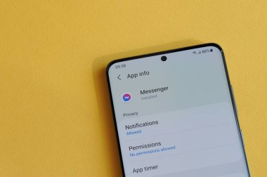 New York, ABD - 12 Nisan 2021: Sarı arka plandaki akıllı telefon ekranında kurye uygulamasında gizlilik ayarları değiştiriliyor