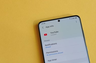 New York, ABD - 12 Nisan 2021: Sarı arka plandaki akıllı telefon ekranında Youtube uygulamasında gizlilik ayarının değiştirilmesi