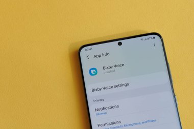 New York, ABD - 12 Nisan 2021: Sarı arka plandaki akıllı telefon ekranında Bixby yardımcı uygulamasında gizlilik ayarının değiştirilmesi