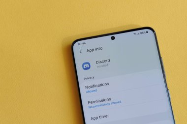 New York, ABD - 12 Nisan 2021: Sarı arka plandaki akıllı telefon ekranında uyumsuzluk uygulamasında gizlilik ayarının değiştirilmesi