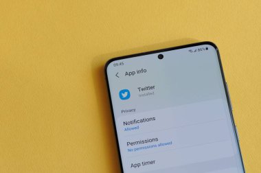 New York, ABD - 12 Nisan 2021: Sarı arka plandaki akıllı telefon ekranında twitter uygulamasında gizlilik ayarının değiştirilmesi