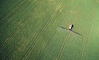 Yeşil çayır hava sahasına kimyasal böcek ilaçları püskürten traktör.