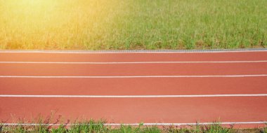 Güneşli çimen arka planında atlet spor şeridi izleri