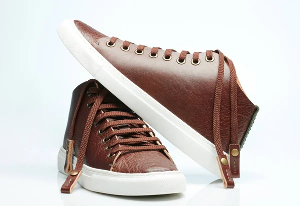Bir çift beyaz tabanlı kahverengi deri spor ayakkabısı.