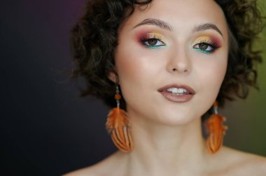 Parlak makyajlı genç bir kadının yakın plan fotoğrafı.