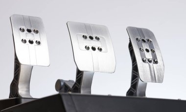 Beyaz arka planda metal parlak araba pedalları. Yarış freni ve gaz pedalı