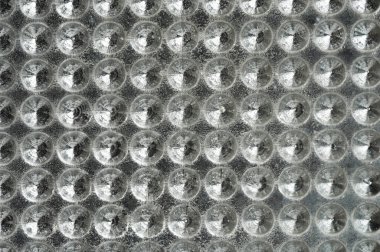 Işığı güzel yansıtan, sanatsal etki yaratan çoklu dairesel şekilleri gösteren desenli yüzeyin yakın görüntüsü.