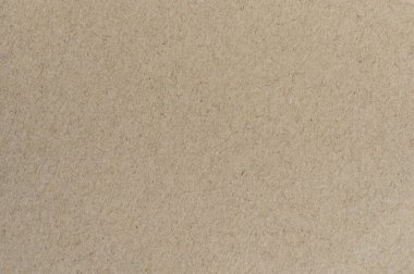 Kahverengi kağıt düz bir yüzey üzerinde doğal ışık altında lifler ve gölgelerle düz bir dokuyu gösterir..