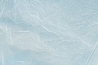 Buruşmuş plastik bir parça düz bir yüzey üzerinde duruyor, ışığın geçmesine ve yumuşak gölgeler oluşturmasına olanak sağlıyor..