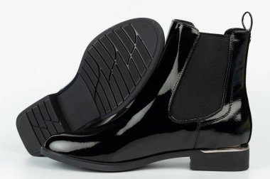 Pürüzsüz bir yüzeye sahip siyah çizmeler düz arkaplanda tabanların ve üst kısmının tasarım ve detaylarını gösterir.