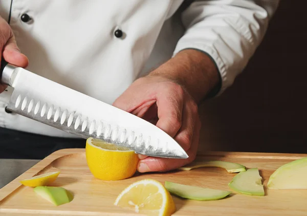 Szef kuchni cięcia cytryny na stole — Zdjęcie stockowe