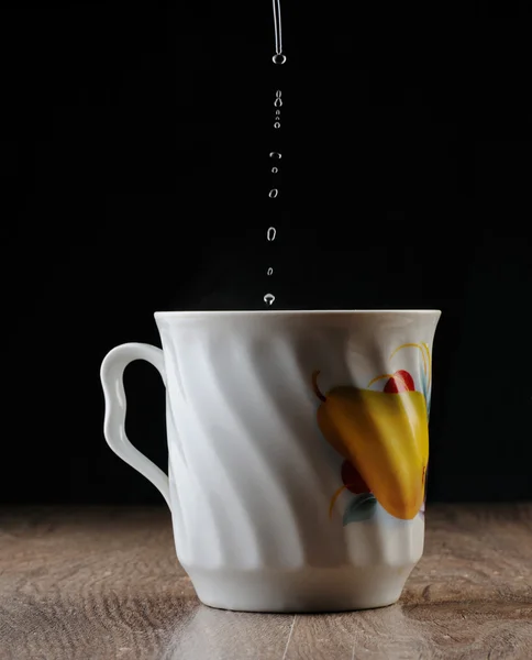 Капли падают в чашку — стоковое фото