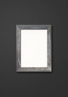 Siyah bir duvarda asılı eski gri ahşap resim çerçevesi. Boş model şablonu