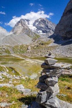 Cairn in front of the Cow lake, Lac des Vaches, in Vanoise national Park, French Alps clipart