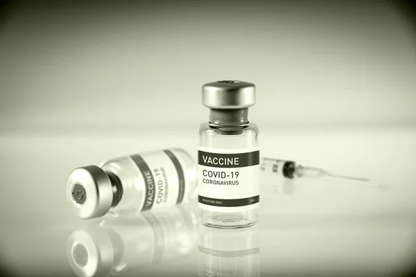 Covid-19 vaccine bottle and syringe on a black and white laboratory background