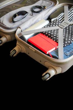 Siyah arka planda izole edilmiş giysilerle dolu bir valizi aç