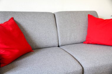 Kırmızı yastıklı gri kanepe.