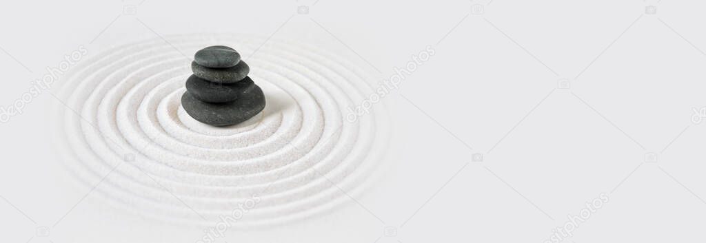 Black stones pile in the sand. Zen japanese garden background scene. Horizontal banner