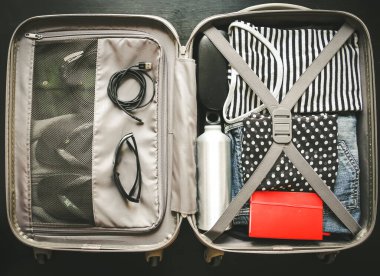 Siyah arka planda izole edilmiş giysilerle dolu bir valizi aç