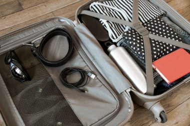 Tahta arka planda izole edilmiş giysilerle dolu bir valizi aç.