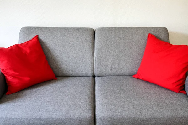 Kırmızı yastıklı gri kanepe.