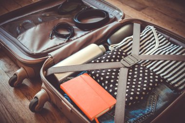 Tahta arka planda izole edilmiş giysilerle dolu bir valizi aç.