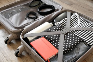 Tahta arka planda izole edilmiş giysilerle dolu bir valizi aç.