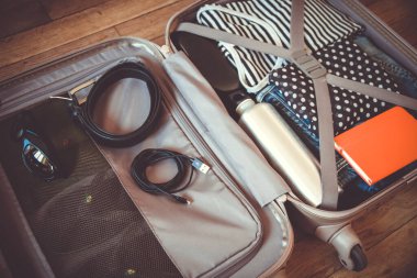 Tahta arka planda izole edilmiş giysilerle dolu bir valizi aç.