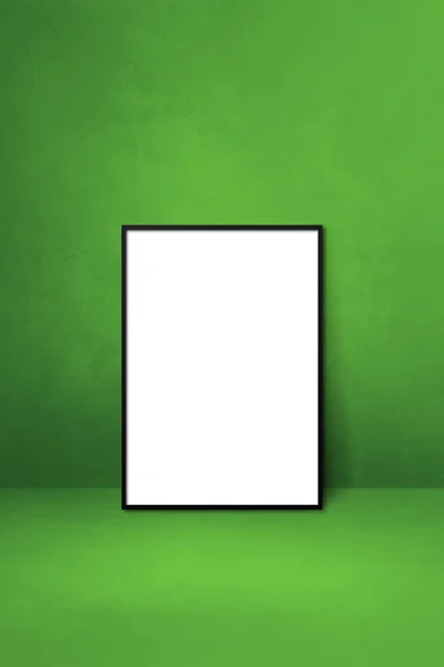 Black picture frame leaning on a green wall. Blank mockup template