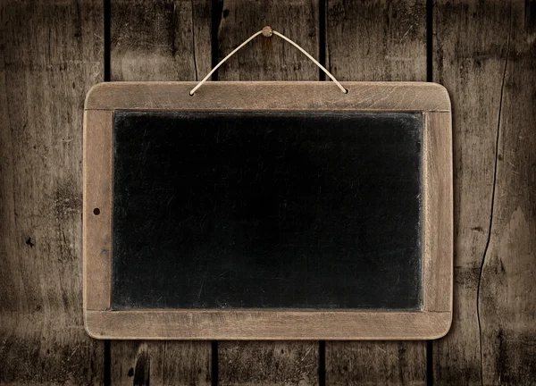 Blackboard on a dark wood wall background — Stock Photo, Image